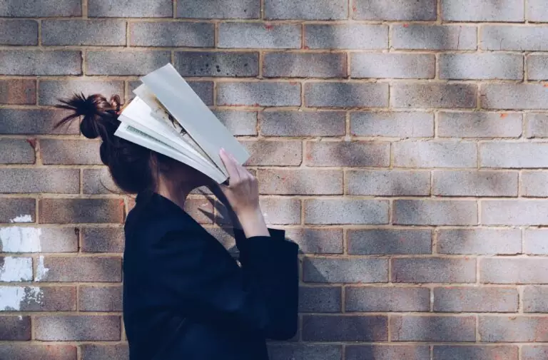 A woman is shown covering her face with a book. Swap school stress for cannabis calm